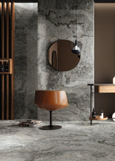 Modern interior with round mirrors, wooden chairs, and a small table against a marble wall.