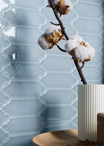 Decorative wall with blue ceramic tiles, cotton branches, and a vase.